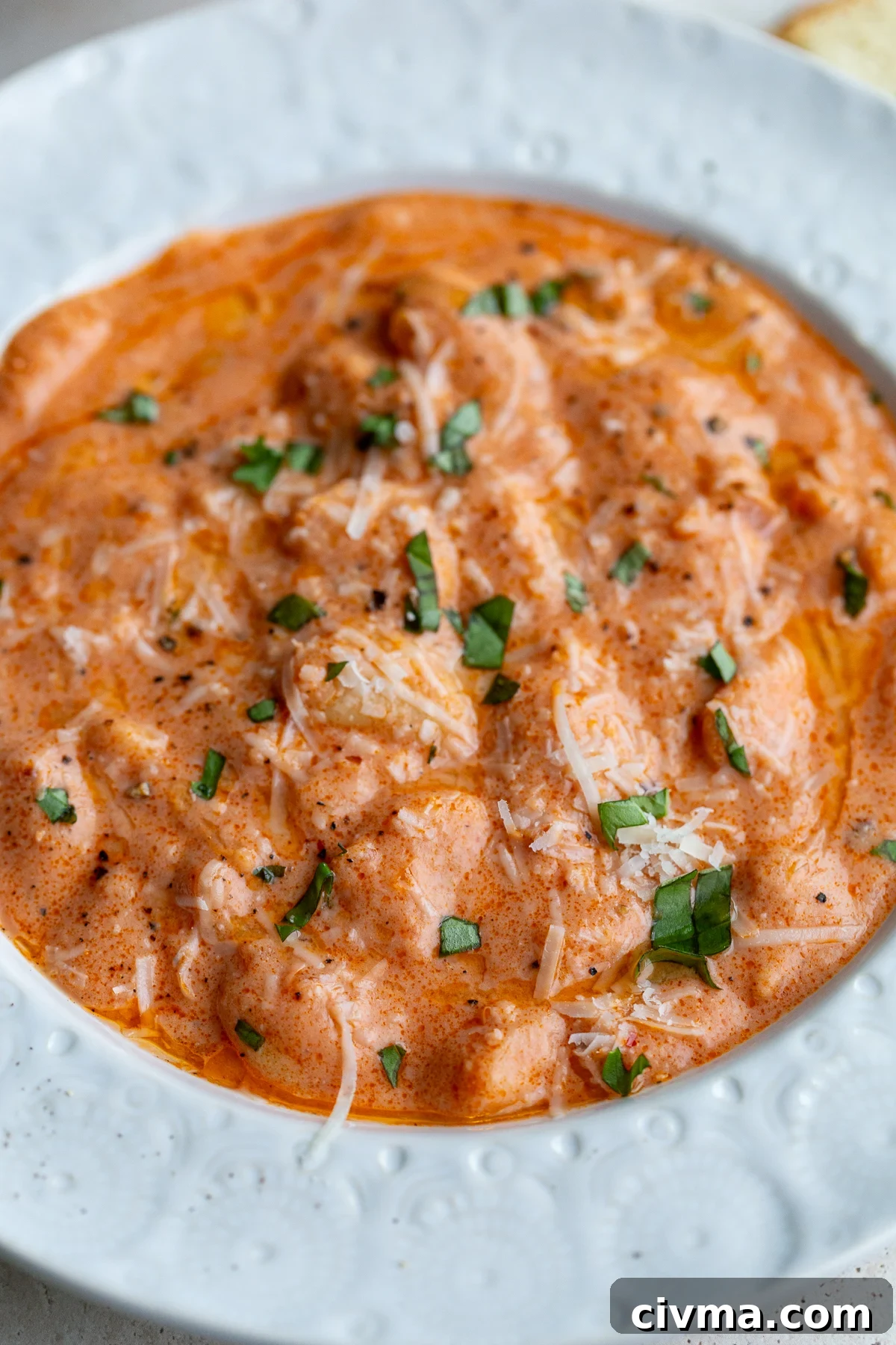 vodka sauce butter beans in a white bowl topped with basil and parmesan cheese