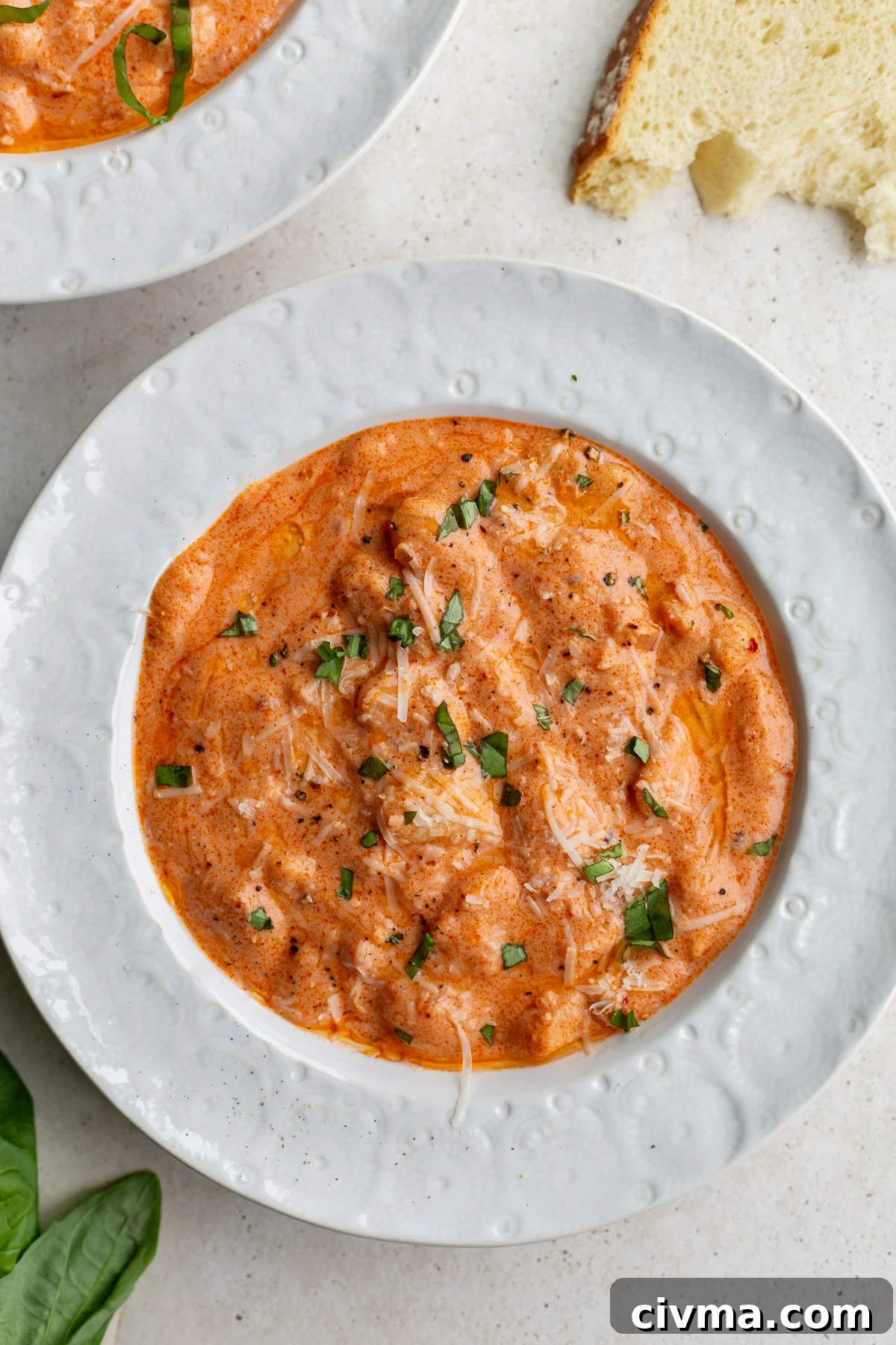 vodka sauce butter beans in a white bowl topped with basil and parmesan cheese