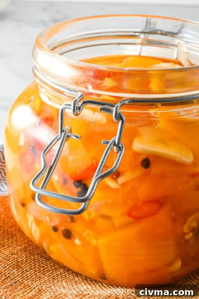 Side view of preserves jar filled with orange vegetables and garlic