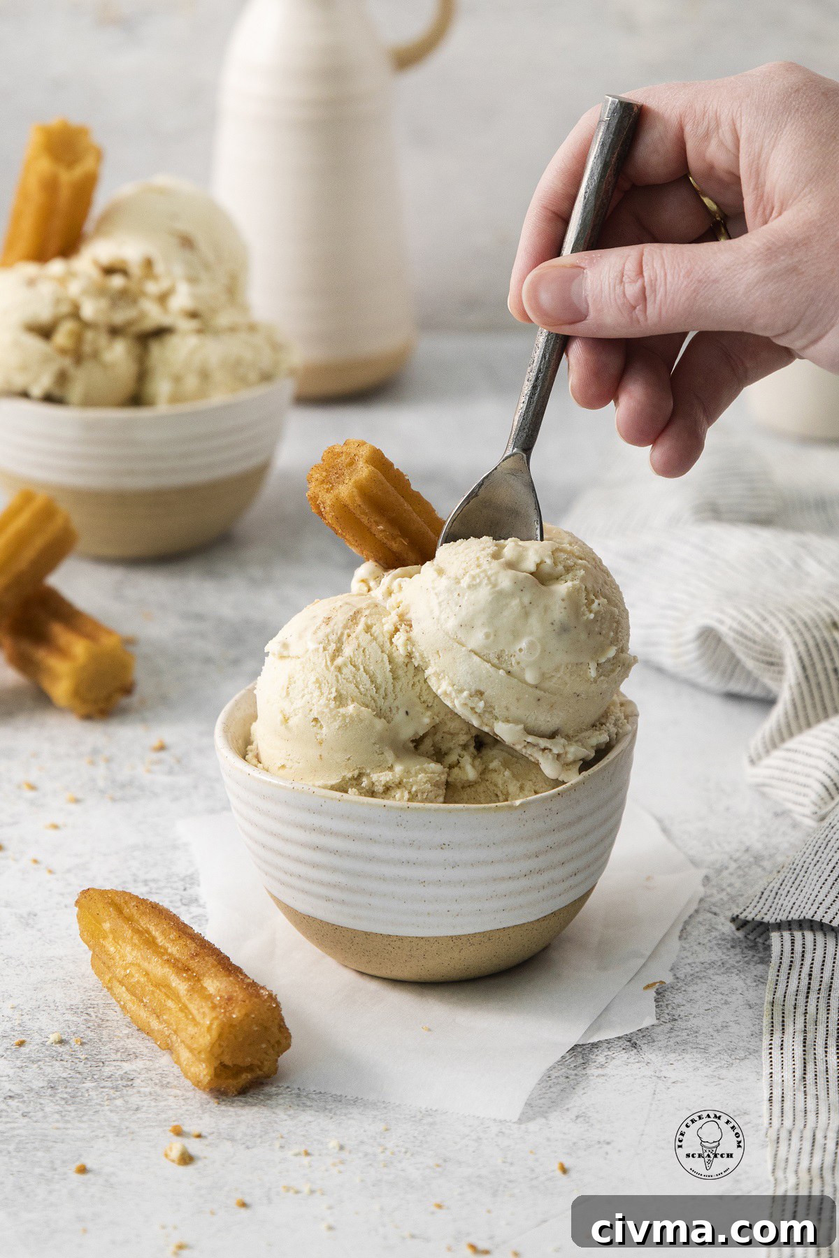 a bowl of homemade ice cream and churros. a hand is eating it with a spoon.