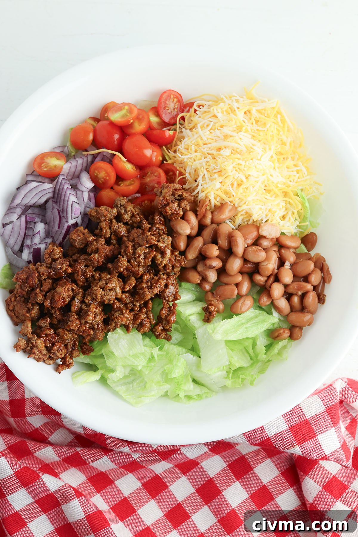 Dorito Taco Salad Recipe with Ground Beef and Catalina Dressing 5 Lettuce, tomatoes, beans, red onion cheese, and taco meat in a bowl.