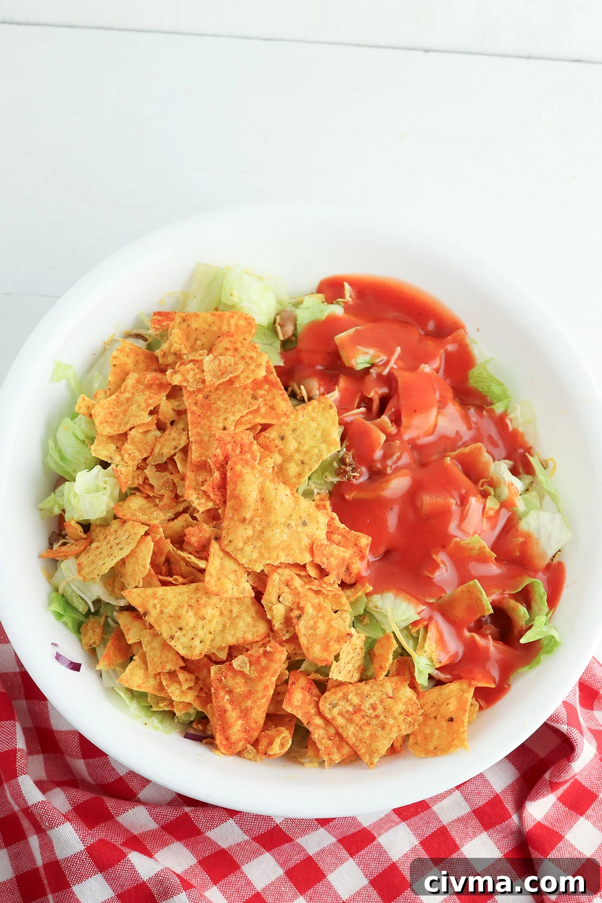 Dorito Taco Salad Recipe with Ground Beef and Catalina Dressing 6 Crushed Doritos and Catalina dressing are added to the taco meat mixture in a bowl.