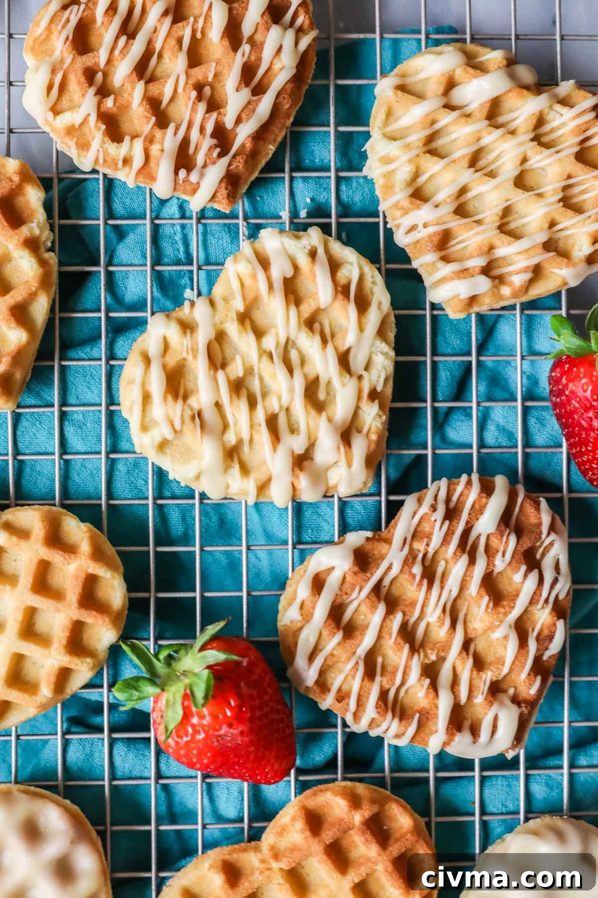 Overhead view of heart shaped waffle cookies on a cooling rack with a turquoise tea towel underneath.