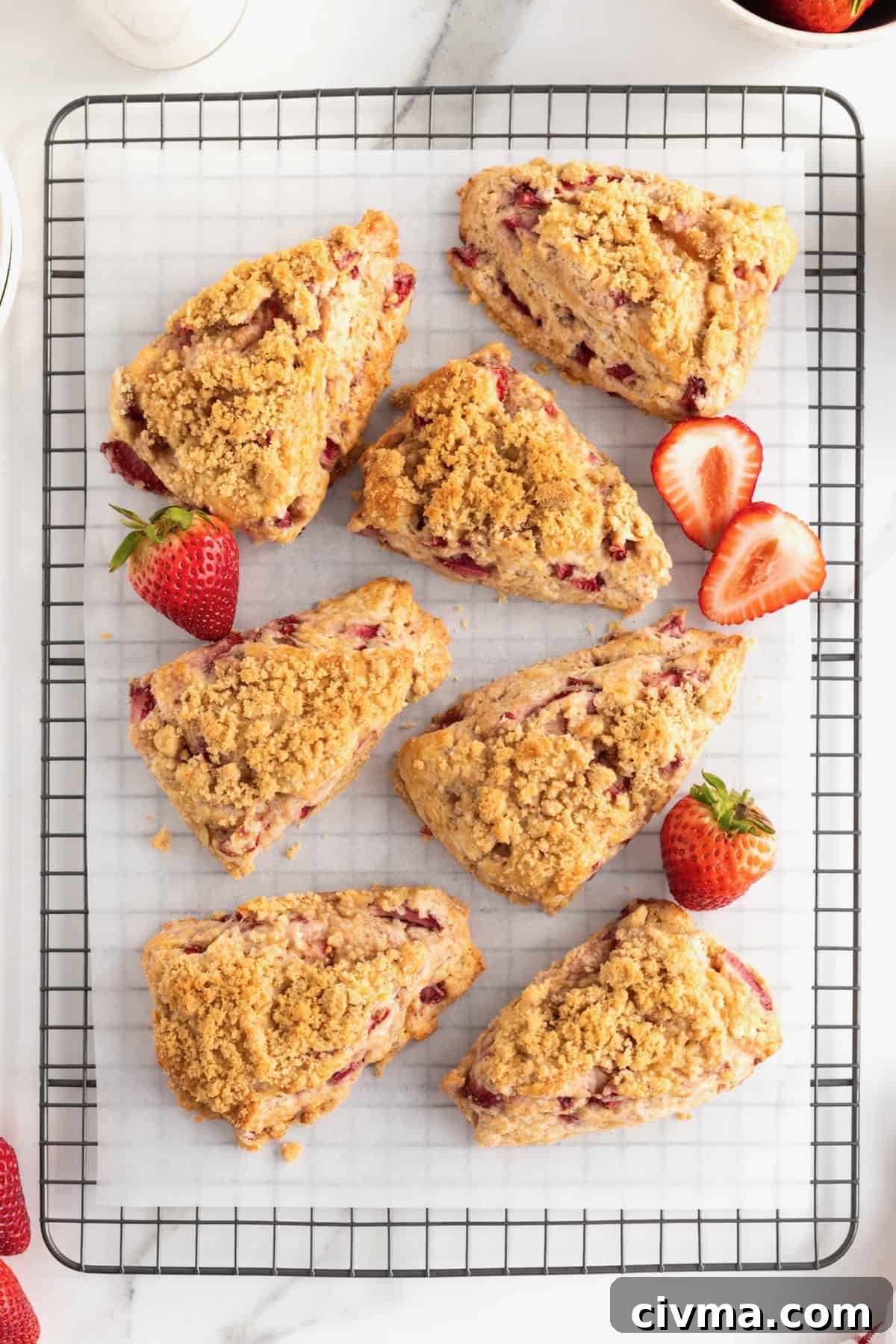 Seven strawberry streusel scones on a parchment-lined cooling rack.