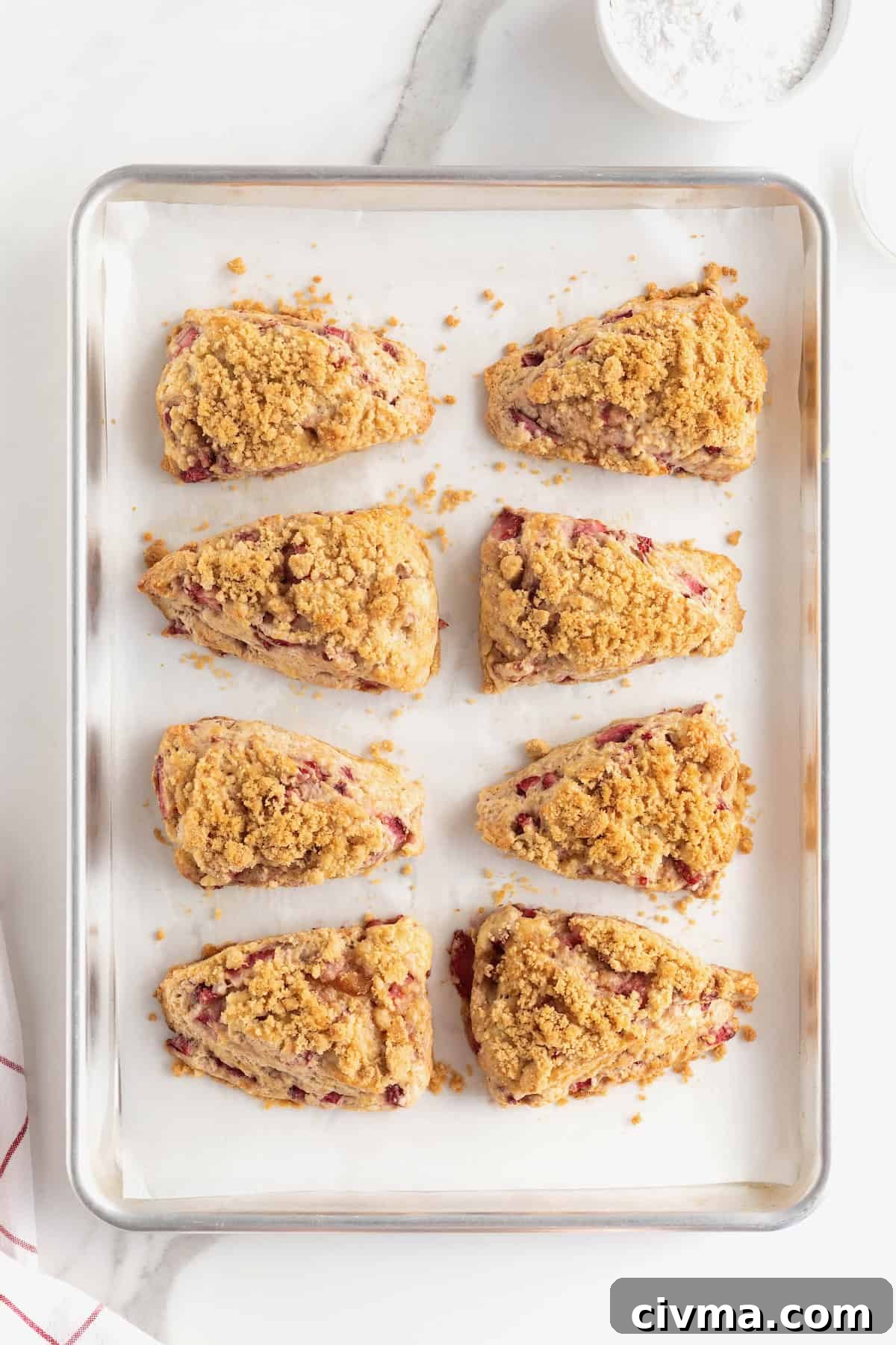 Baked strawberry streusel scones on a parchment-lined baking sheet.