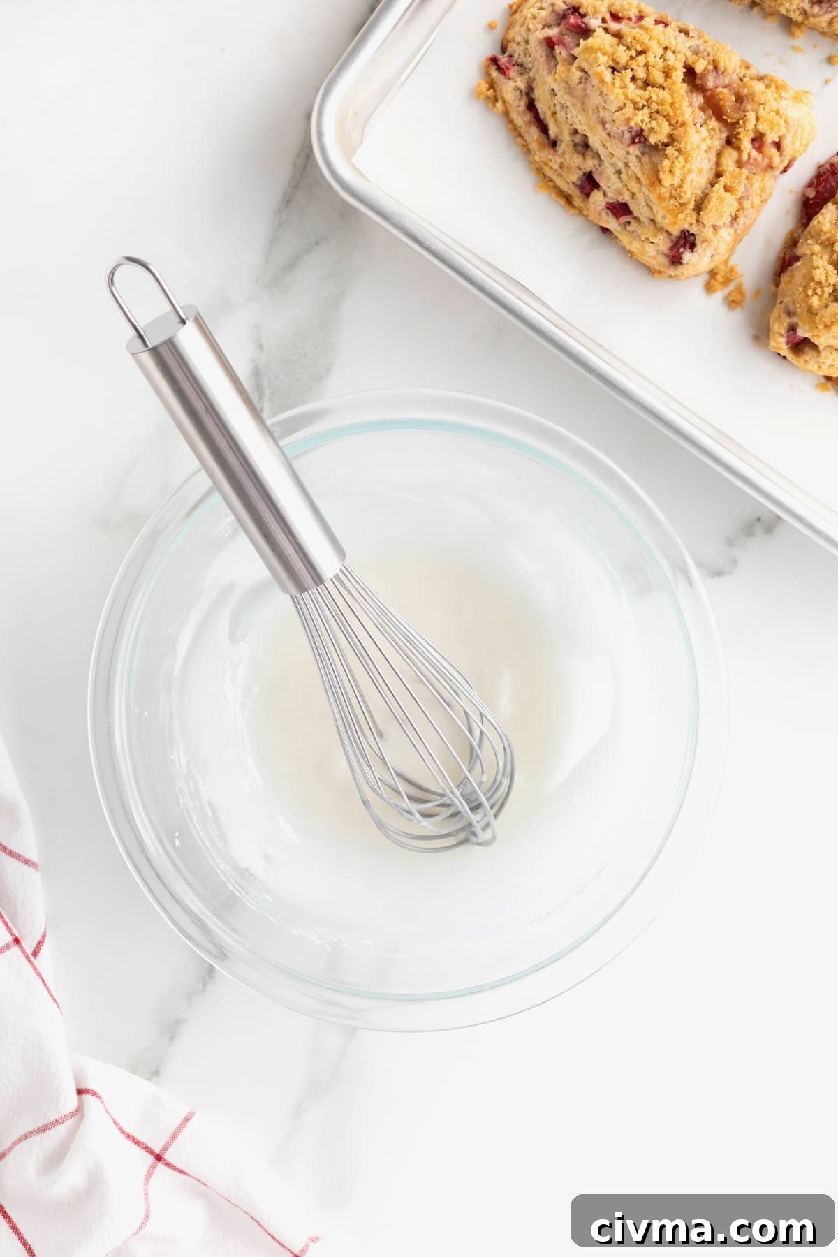 Simple icing in a clear bowl with a whisk.