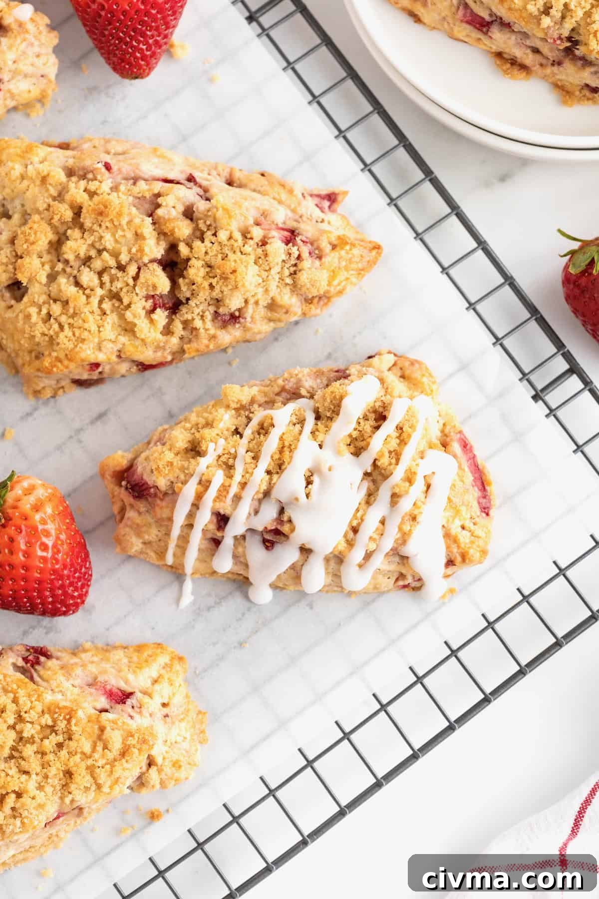Strawberry streusel scones with icing on a cooling rack.