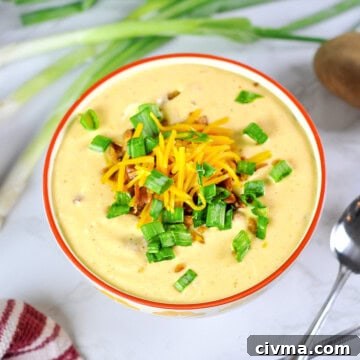 loaded potato soup in a bowl, topped with cheese, green onions, and bacon.
