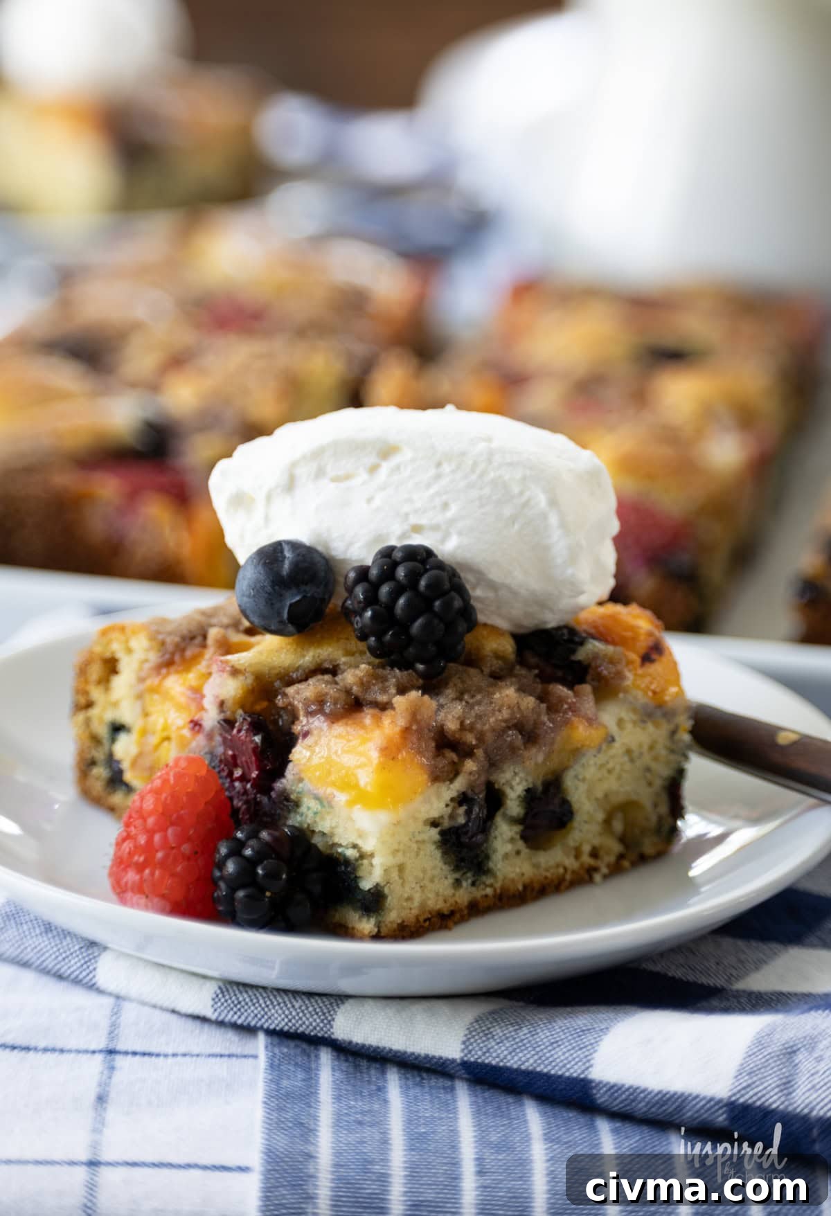 piece of Nectarine and Berry Buckle on a plate with whipped cream.