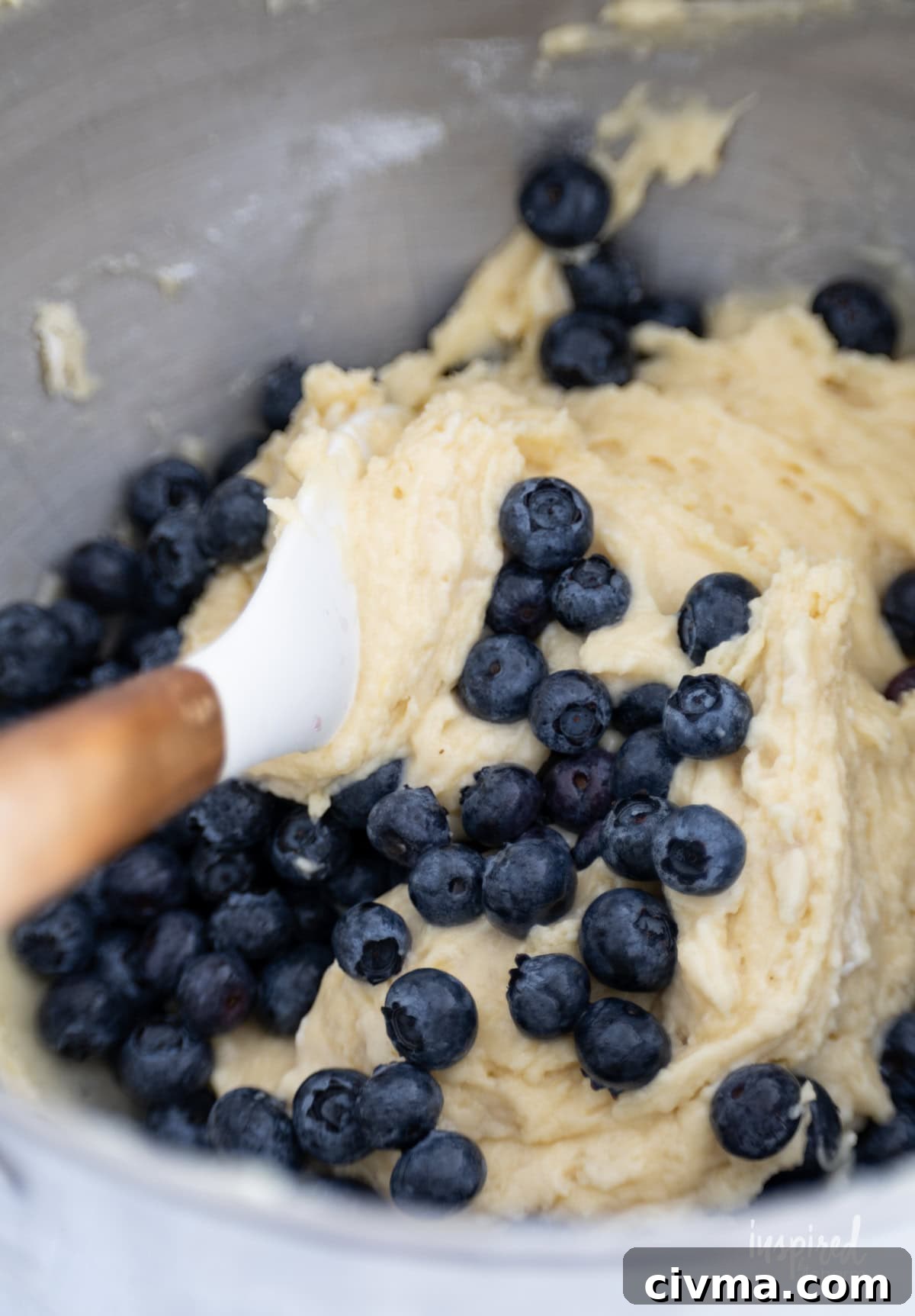 spatula folding blueberries into batter.