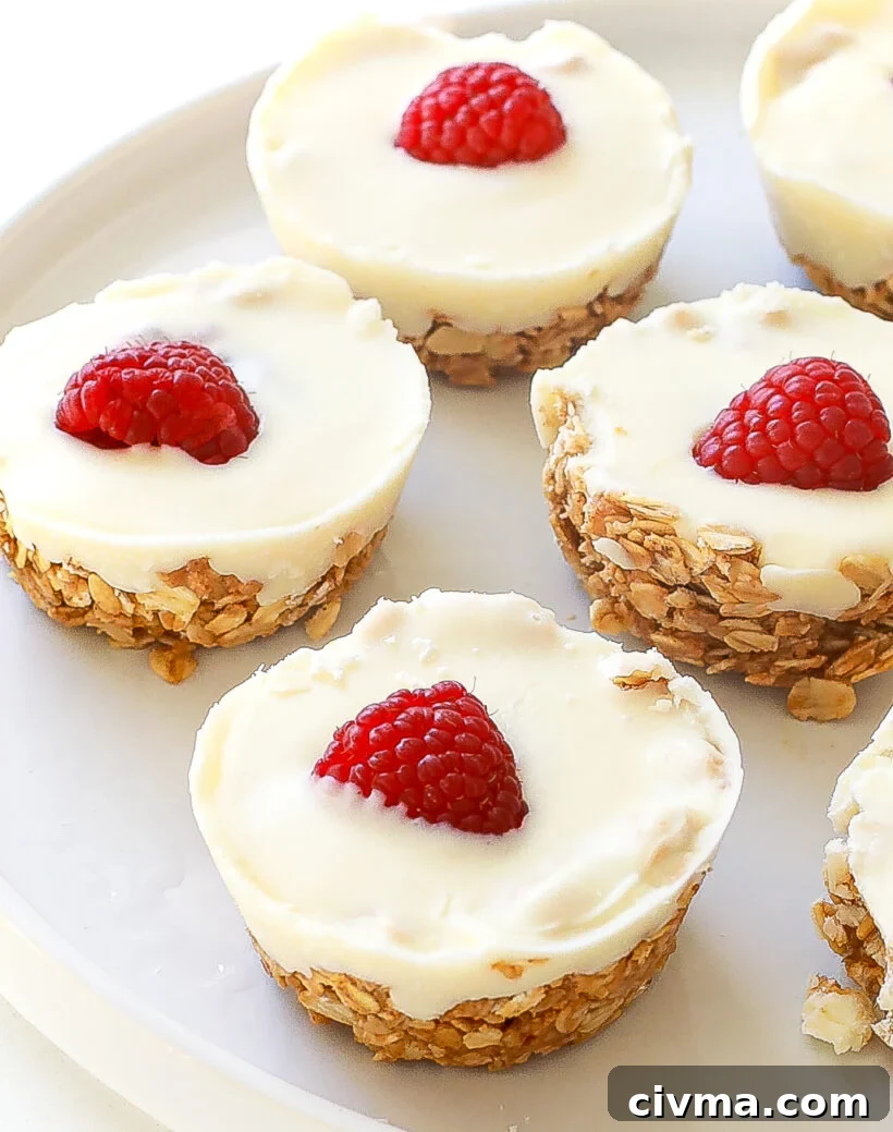 Close up of oat cups with oat mixture topped with white chocolate and a raspberry.