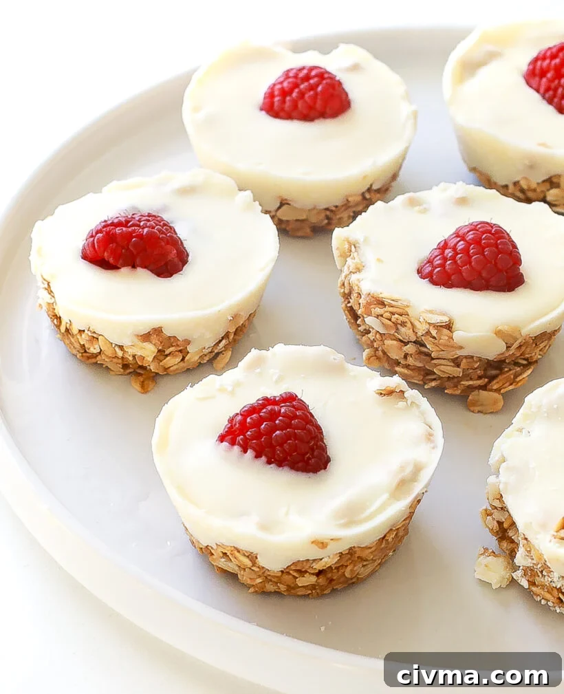 White chocolate oat cups served on a white plate with raspberries on top.