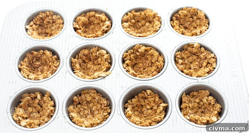 Peanut butter oat mixture pressed into a muffin tin with small wells.