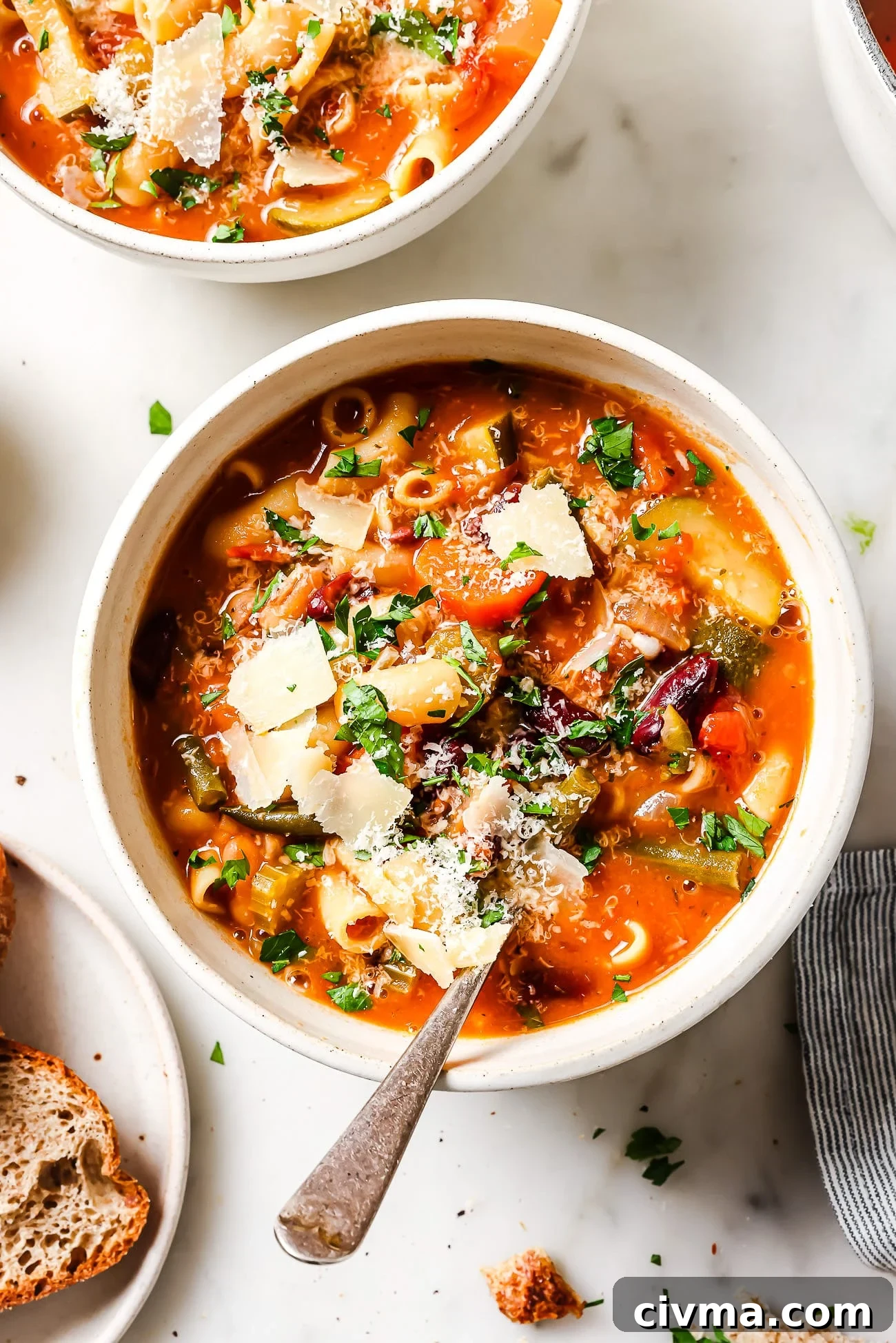 A bowl of Minestrone Soup garnished with fresh parsley and parmesan cheese.
