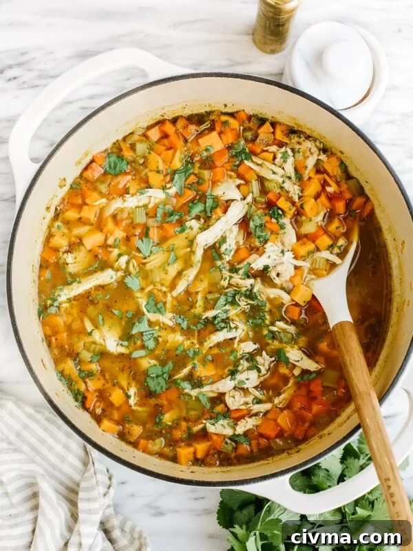 overhead view of sweet potato chicken soup in a white Dutch oven pot