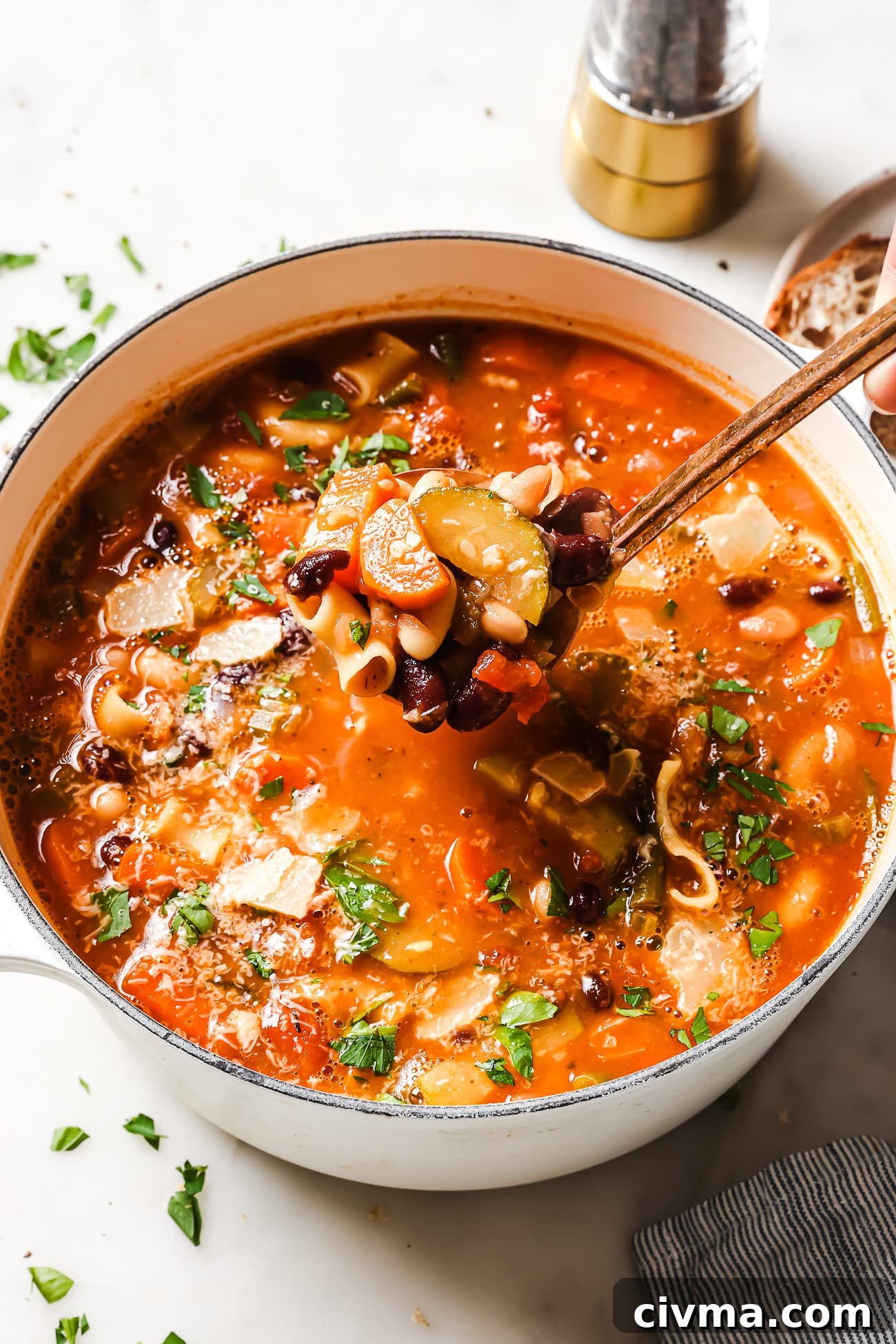 A bowl of Minestrone Soup garnished with fresh parsley and parmesan cheese.