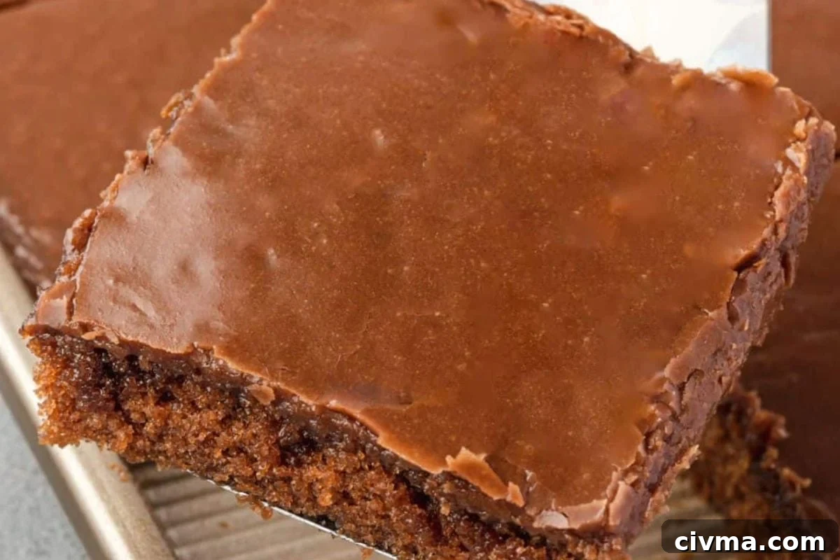 Close-up of a rich chocolate frosted brownie slice on a spatula, showcasing its fudgy texture and glossy icing.