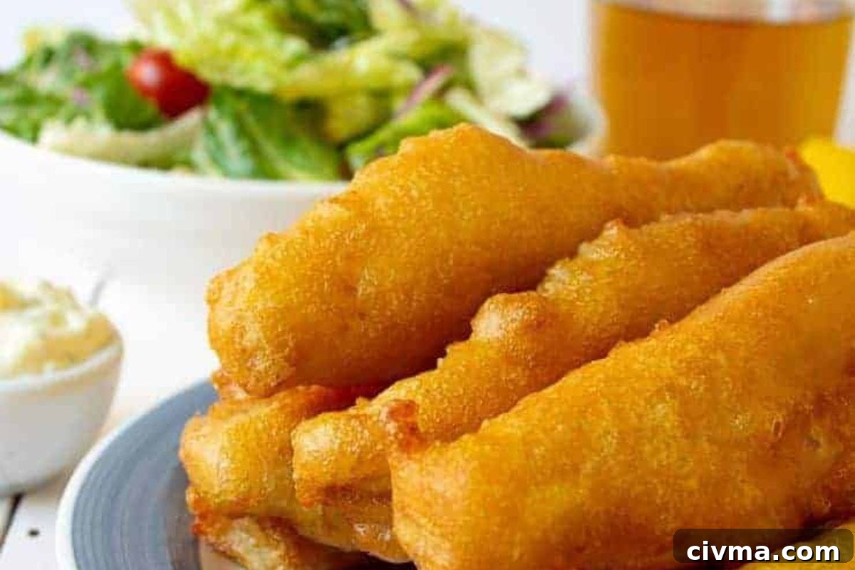 A close-up of golden battered fish sticks served with a side of fresh salad and a small bowl of tartar sauce.