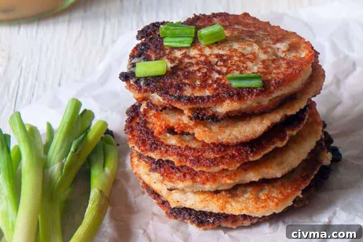 A stack of golden-brown potato pancakes garnished with green onions, alongside fresh green onions.