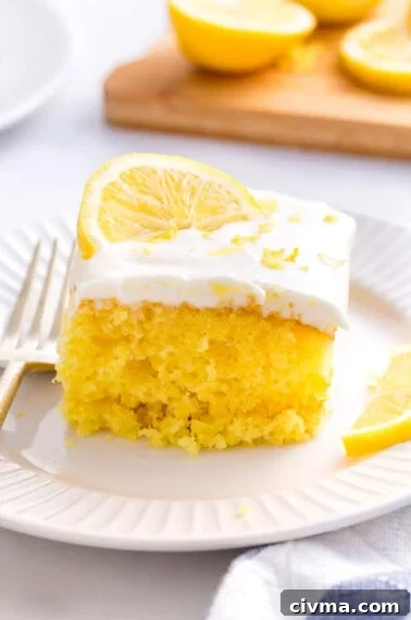 A slice of lemonade cake with lemon frosting and a lemon slice on top.
