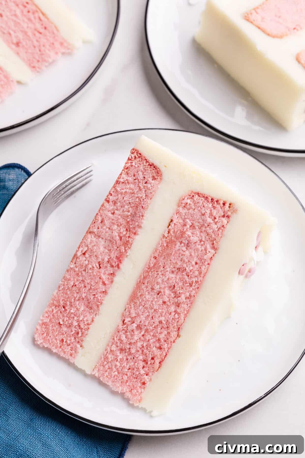 top down image of a slice of pink velvet cake served on a white round plate.