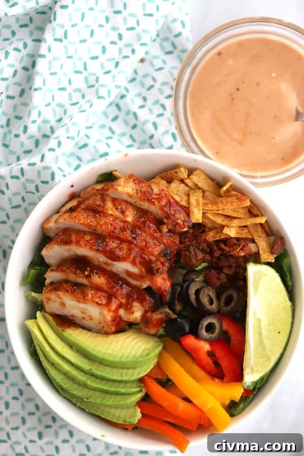 grilled BBQ Chicken Salad ingredients in a white bowl with a ramekin of bbq ranch dressing on the side. bbq ranch salad, bbq chicken chopped salad.