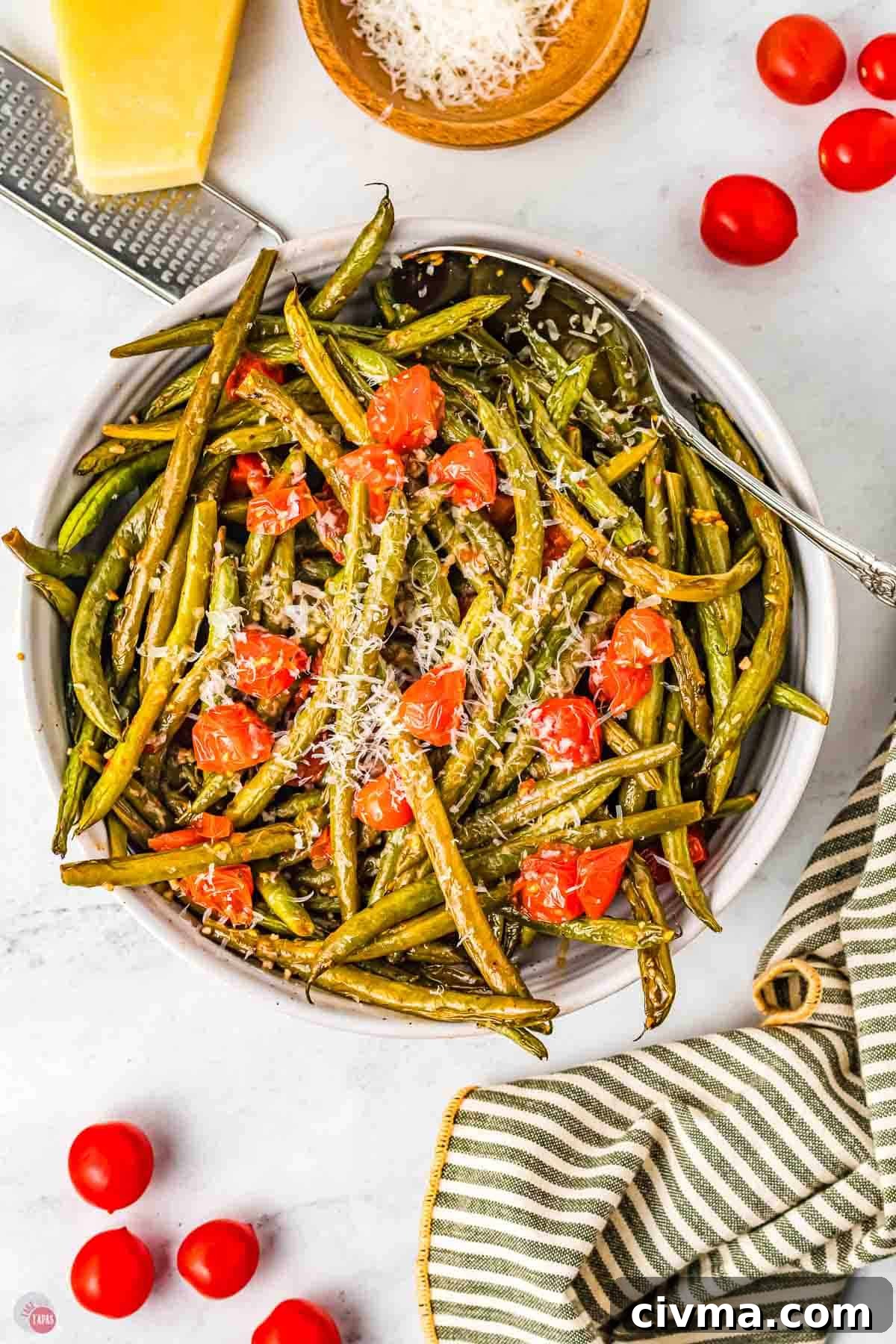 bowl of green beans and tomatoes next to a striped napkin