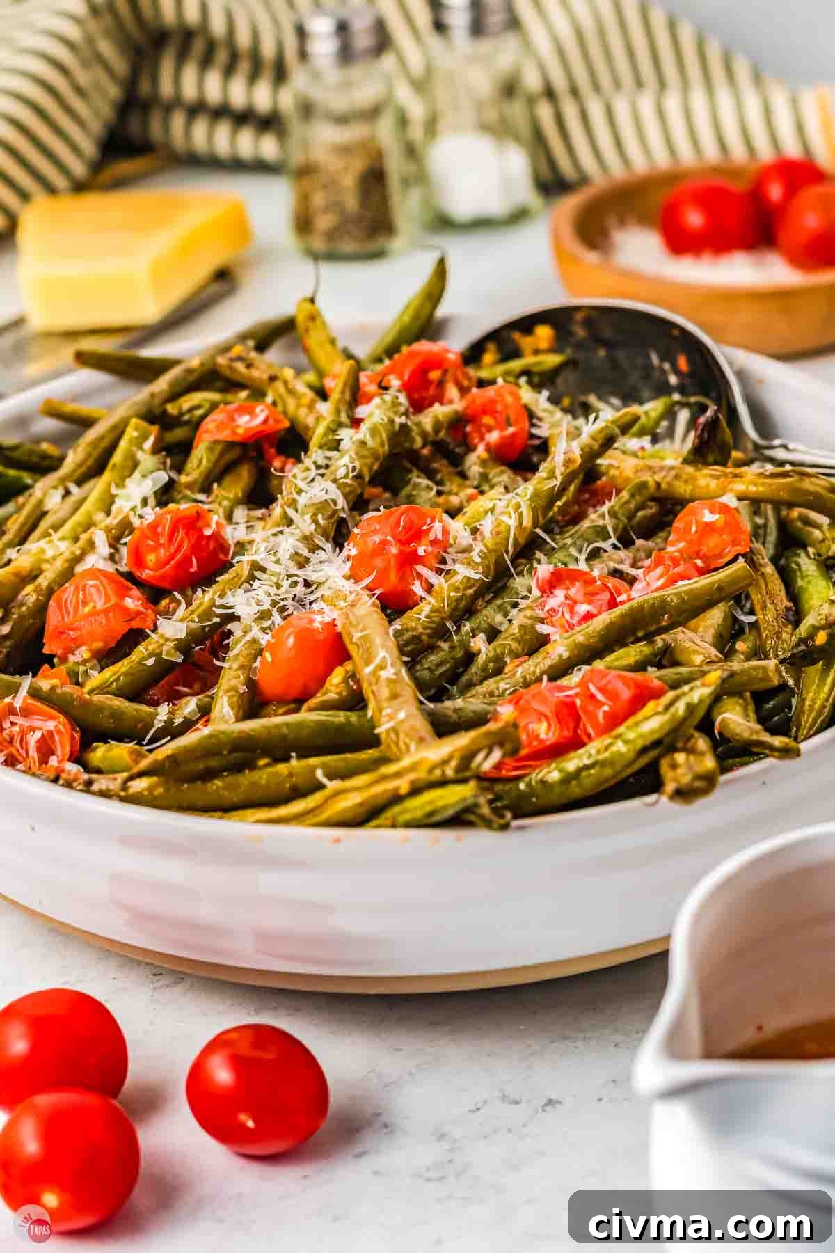 green beans and tomatoes in a large white bowl and topped with shredded cheese