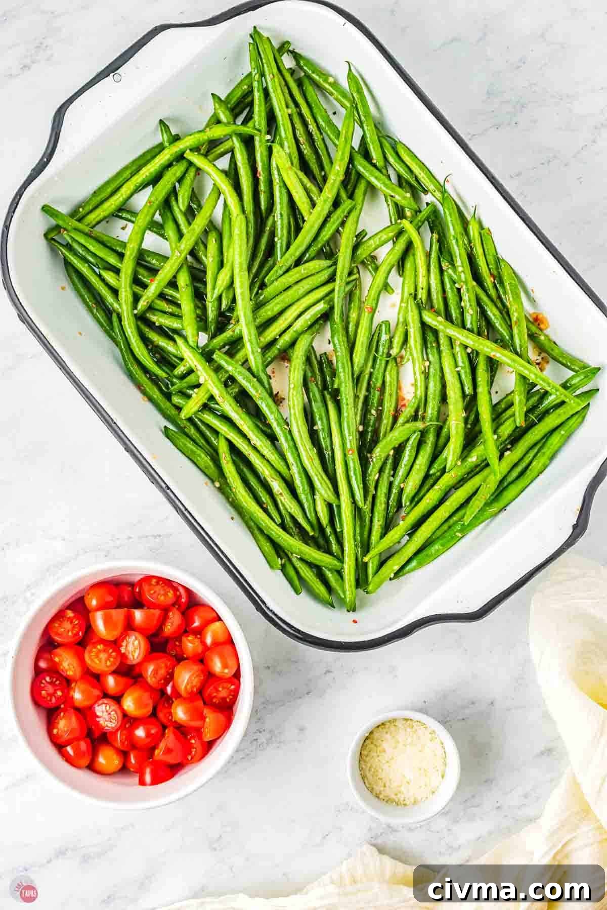 green beans in a baking dish next to a bowl of cut tomatoes