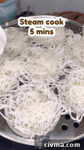 Freshly steamed idiyappam noodles in a stainless steel tray for traditional South Indian breakfast.