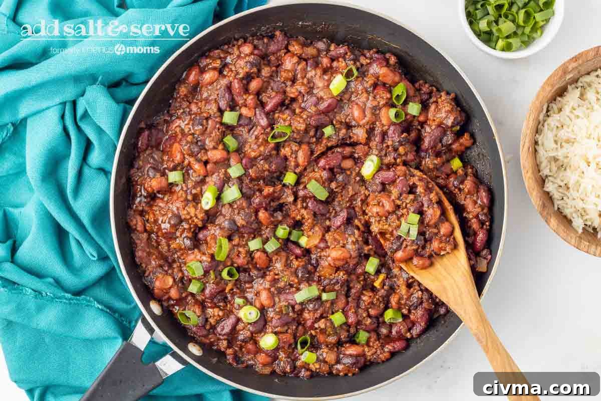 30 Minute BBQ Beef and Beans Recipe 6 Beef and beans garnished with green onion in a skillet with a wooden spoon.