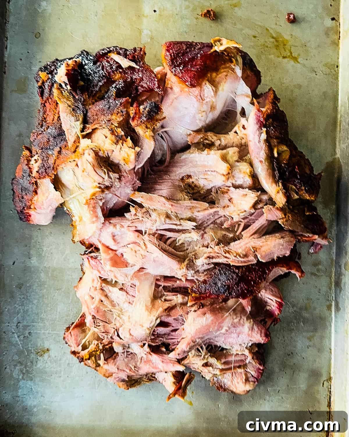 The roast falling apart by itself on a baking sheet.
