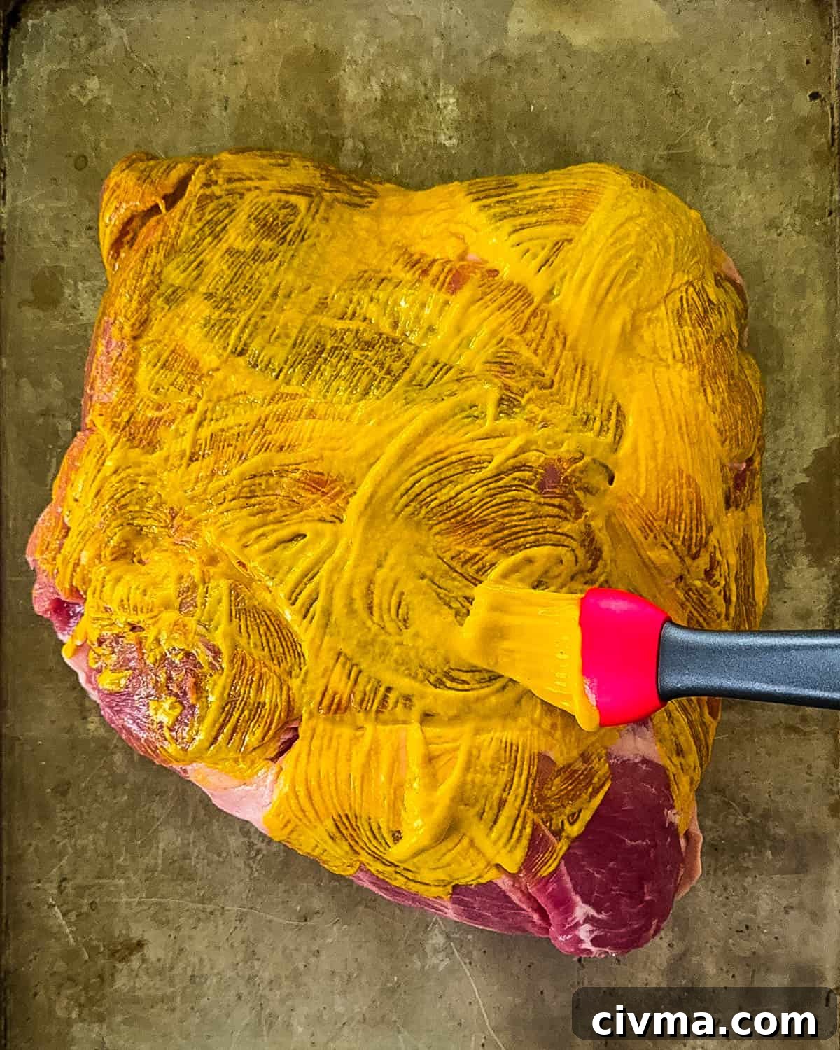 Meat being brushed with yellow mustard.