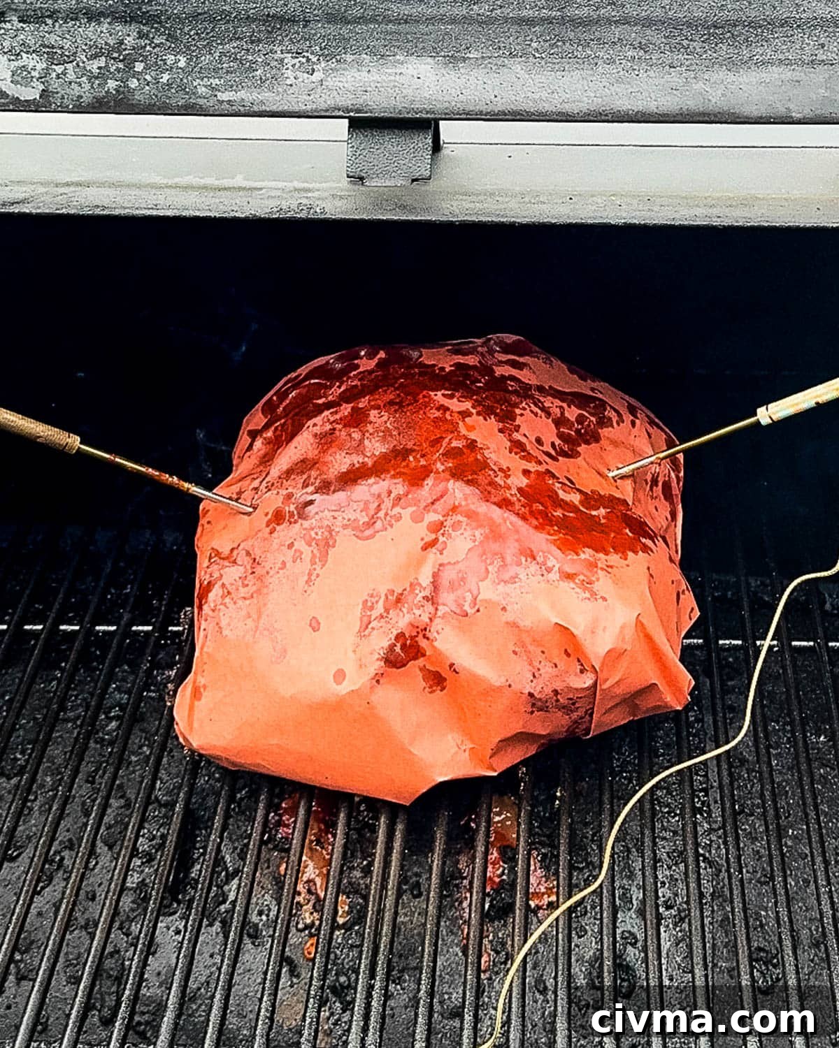 The wrapped pork on the pellet grill with temperature probes inserted.