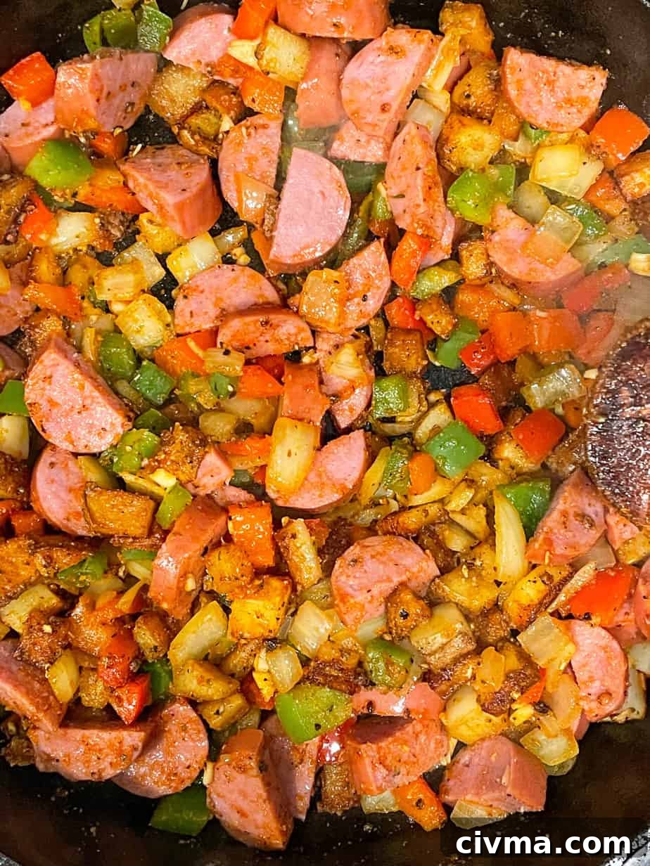 Smoked sausage cooking with potatoes and vegetables.