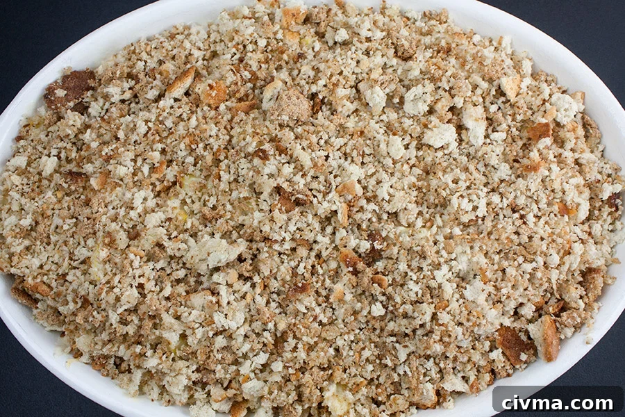 Southern Yellow Squash Casserole in an oval white casserole topped with bread crumbs
