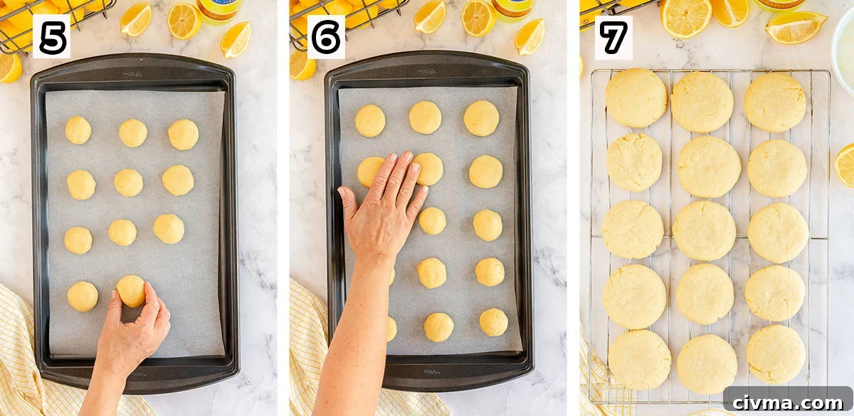 A hand flattens balls of cookie dough on a baking sheet.