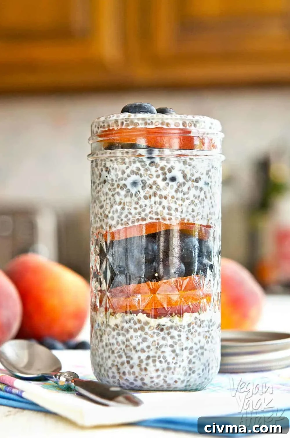 Blueberry peach chia parfait in a glass jar on a floral linen