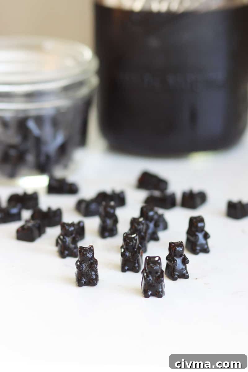 a bunch of elderberry gummies on a counter with a jar of elderberry syrup behind them