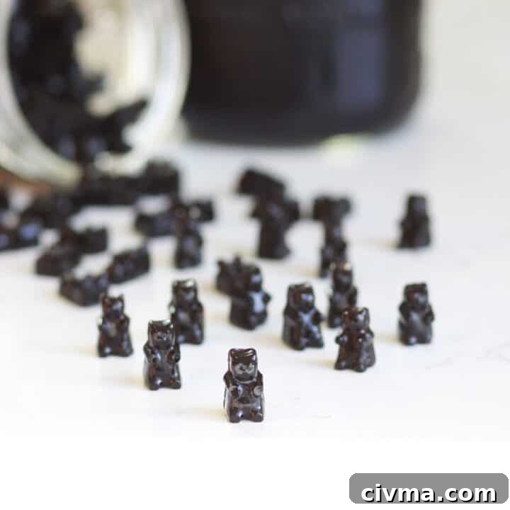 a bunch of elderberry gummies on a counter with a jar of elderberry syrup behind them