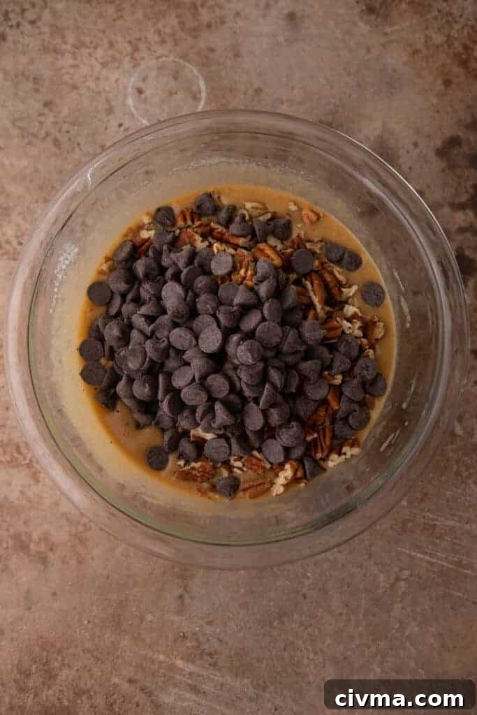 chocolate chips and pecans on top of raw filling ingredients in a bowl