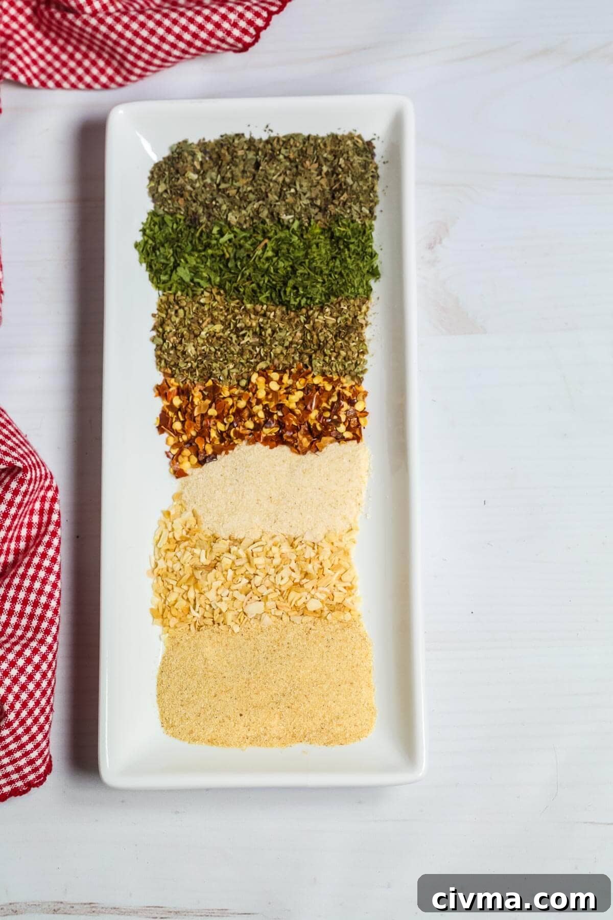 A line of the different spices on a square white plate.