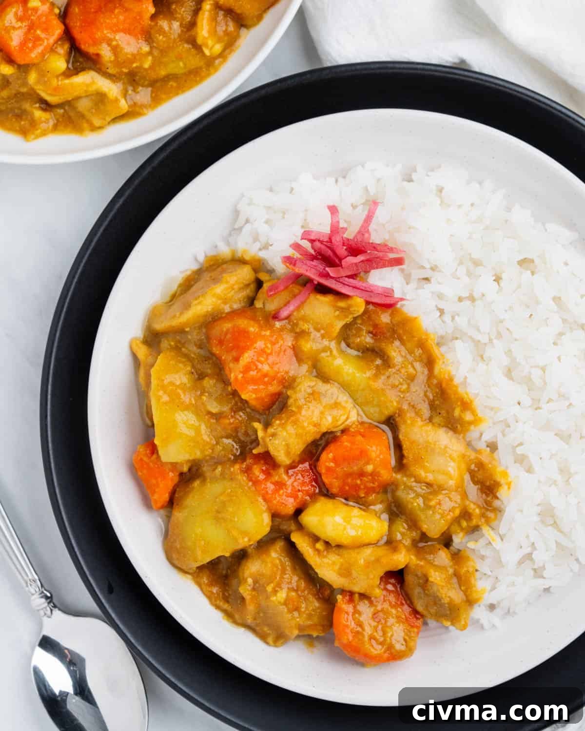 Plate of Japanese curry on top of rice with pickled ginger.