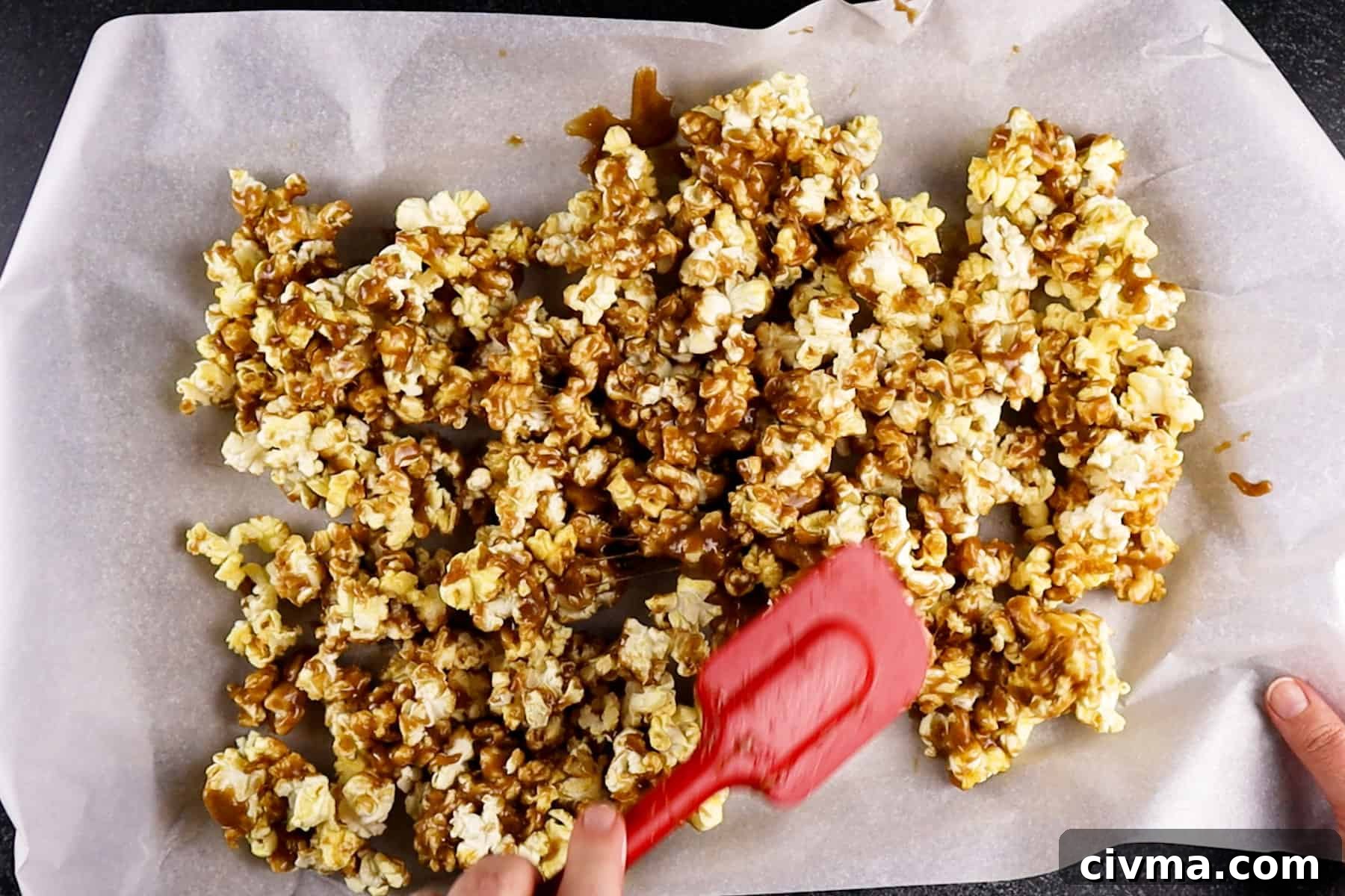Homemade Caramel Popcorn Recipe 12 stirring popcorn on baking sheet after it has baked for 15 minutes