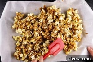 Homemade Caramel Popcorn Recipe 25 stirring popcorn on baking sheet after it has baked for 15 minutes
