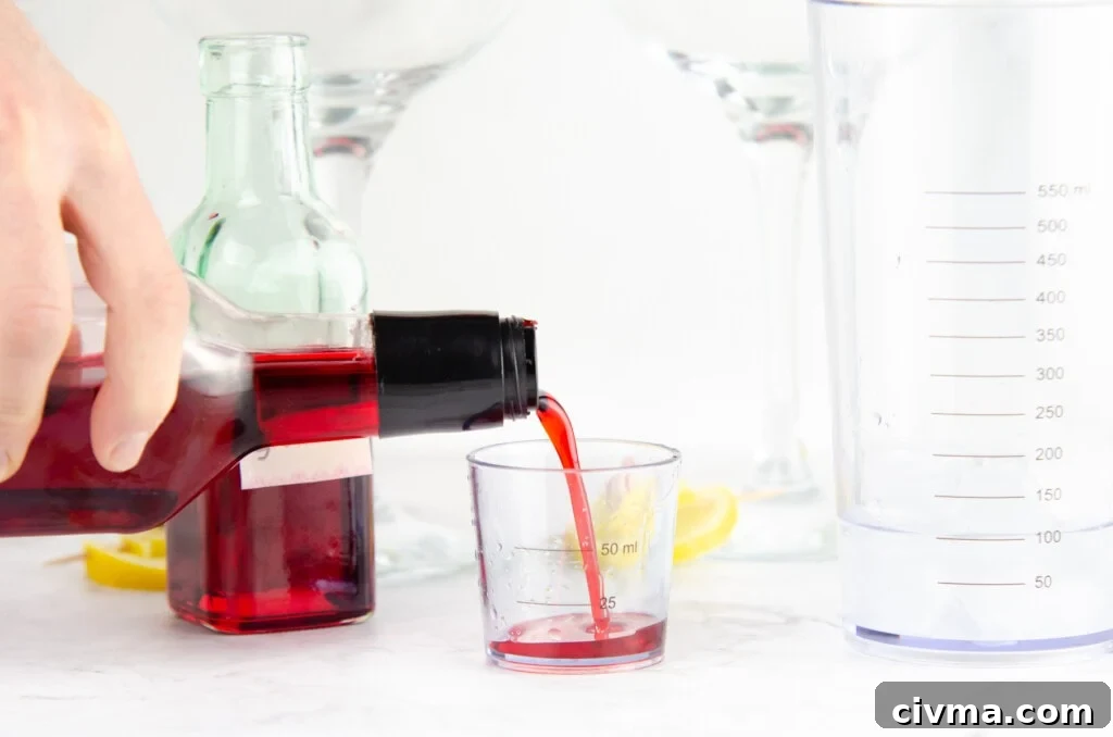 Pouring grenadine into a measuring cup to place in the cocktail shaker with the gin
