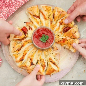 Pulling away the Puff pastry pizza wheel segments with melted cheese dripping away from the pastry