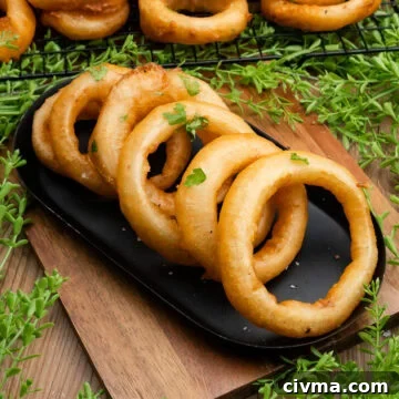 Six beer battered onion rings served in a black metal dish with salt and fresh parsley over the top