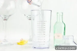 Pouring gin into a cocktail shaker with two glasses and a green bottle of gin the background
