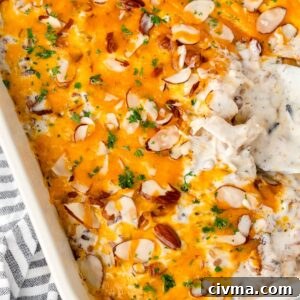 Close-up of a Chicken and Wild Rice Casserole melted cheese and sliced almonds in a baking dish.